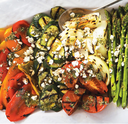 A selection of grilled summer vegetables including zucchini, egglplant and red peppers arranged beautifully on a platter.