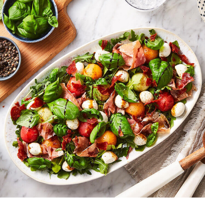 Melon and prosciutto chopped summer salad in a white salad bowl.