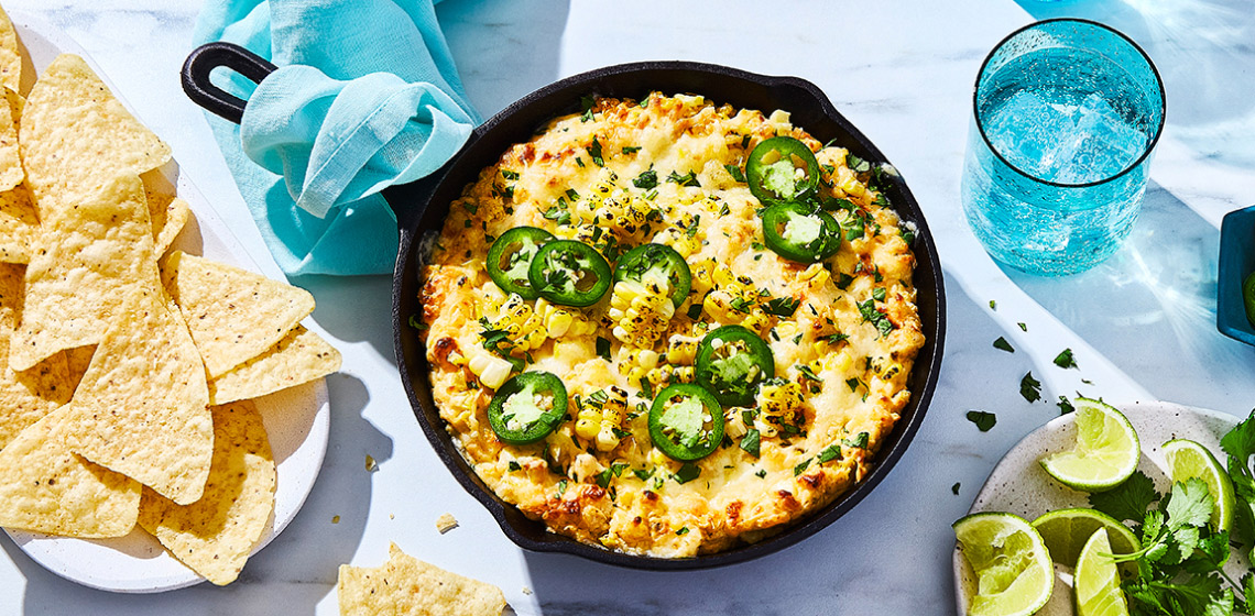 Mexican street corn-inspired party dip in a cast iron serving pan on summer table