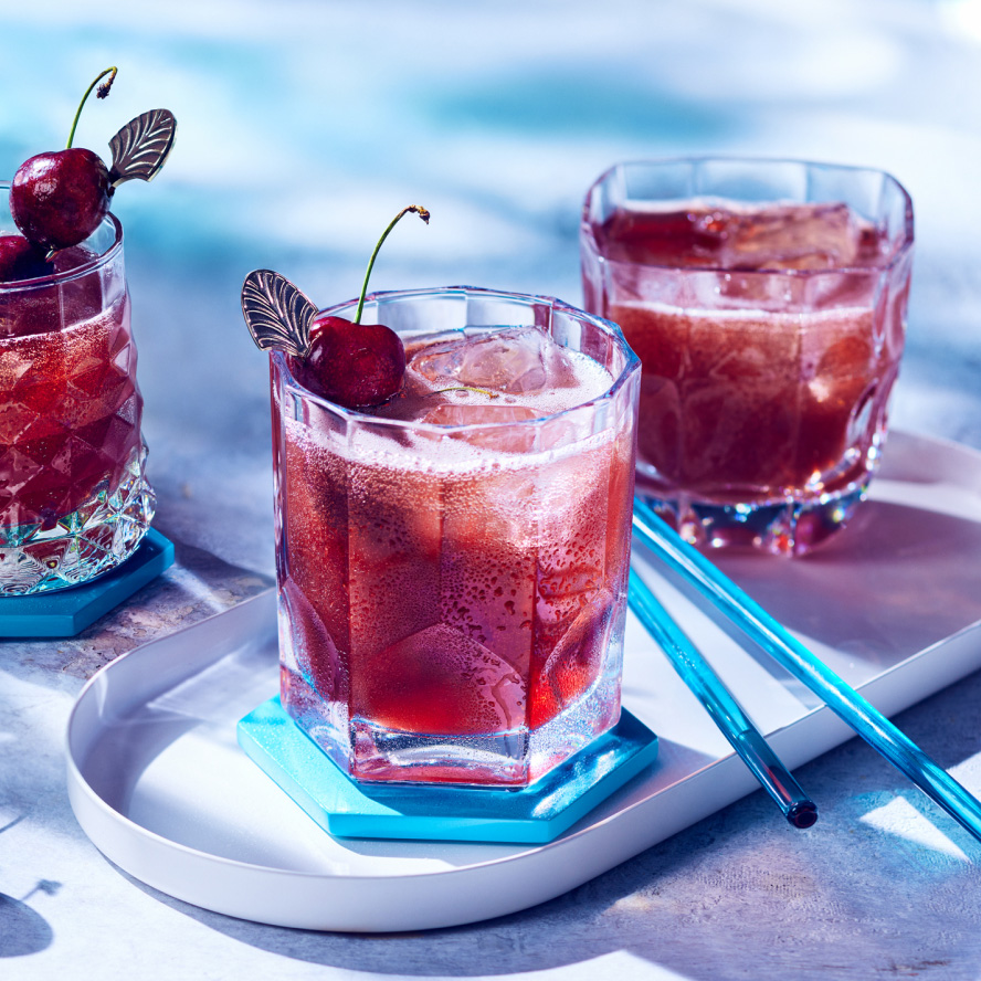 three short glasses of a spritzy cherry and rye cocktail