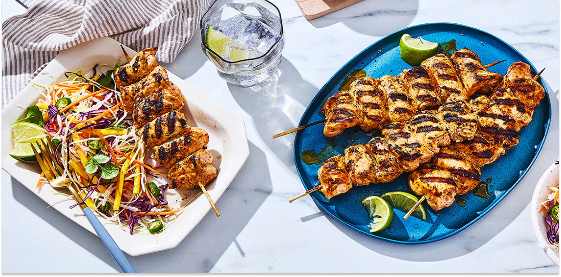 Two platters of grilled tropical-glazed chicken kabobs on marble surface