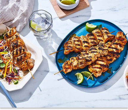 Two platters of grilled tropical-glazed chicken kabobs on marble surface