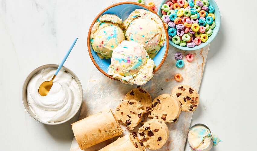 Compliments Birthday Cake Flavour Light ice cream layered between baked chocolate chip cookie layers and topped with more ice cream and sprinkles with one slice cut out of â€œcake.â€