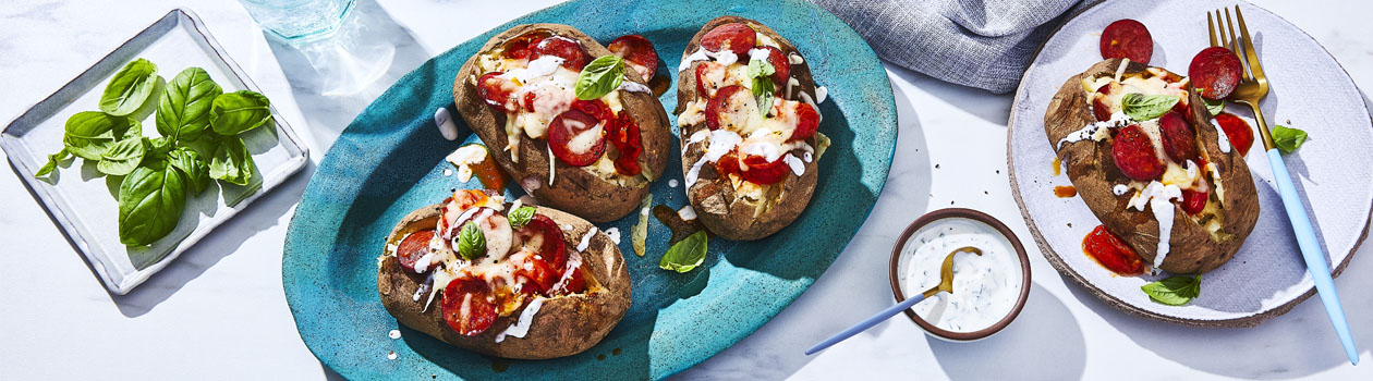 blue oval platter of three pepperoni pizza baked potatoes with ranch drizzle