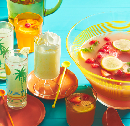 https://www.compliments.ca/en/article/3-ways-with-lemonade/ aqua blue wooden table top with yellow tray, holding glasses of iced lemonade, whipped lemonade, and and lemonade punch