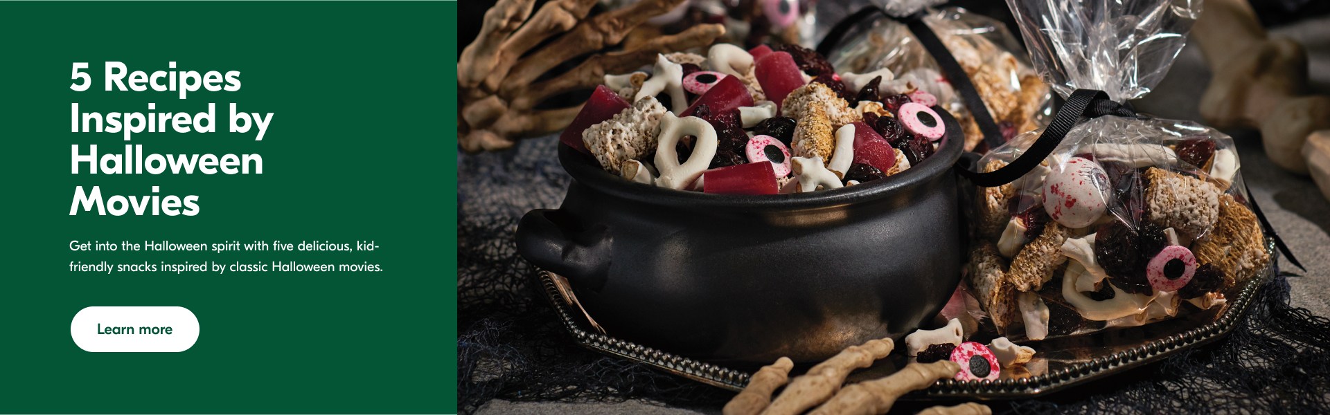 Bag of bones treat mix in a cauldron and clear bags on a black tray